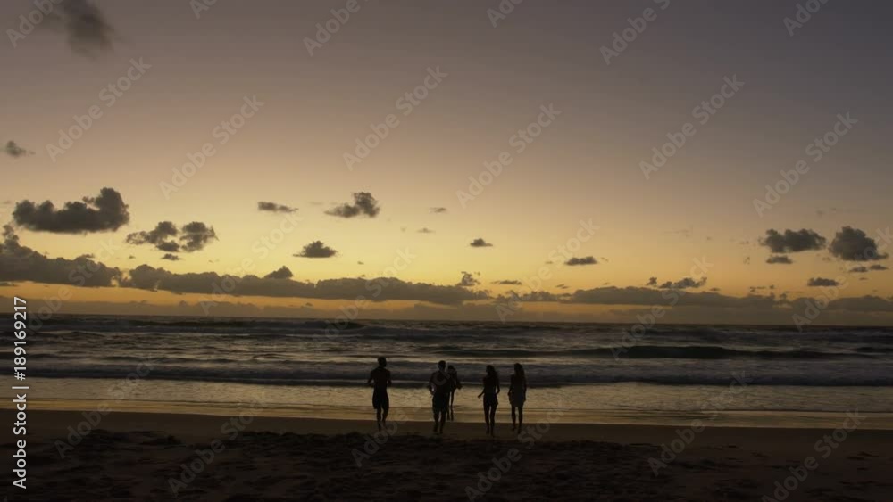 Friends Running into Water on Beach at Sunrise. Silhouette. Slowmotion. Friends Running into Water on Beach at Sunrise. Silhouette. Slowmotion.