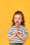 portrait of preteen child eating lollipop isolated on yellow