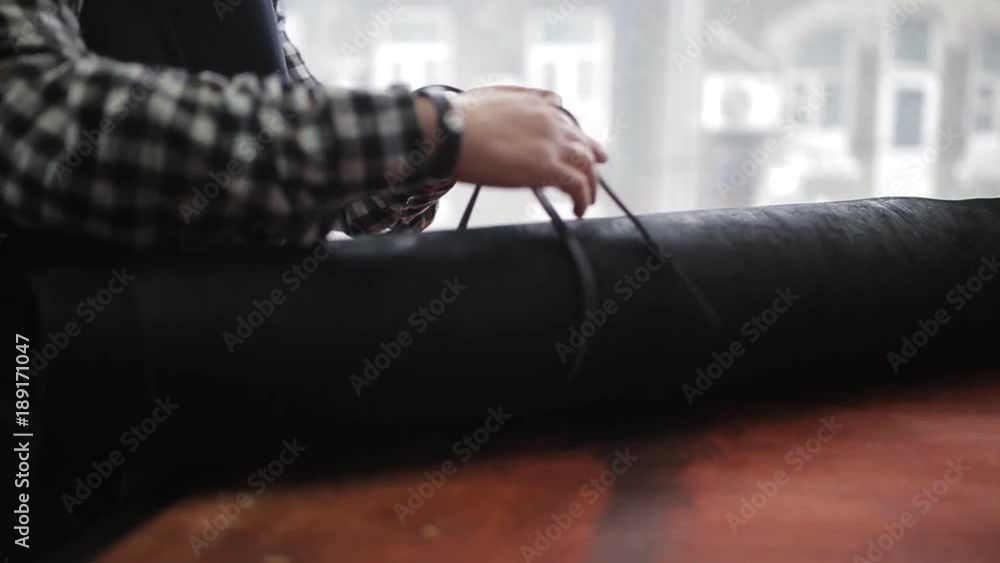 The man in the workshop of the Tanner lays on the table a roll of processed animal skin The man in the workshop of the Tanner lays on the table a roll of processed animal skin