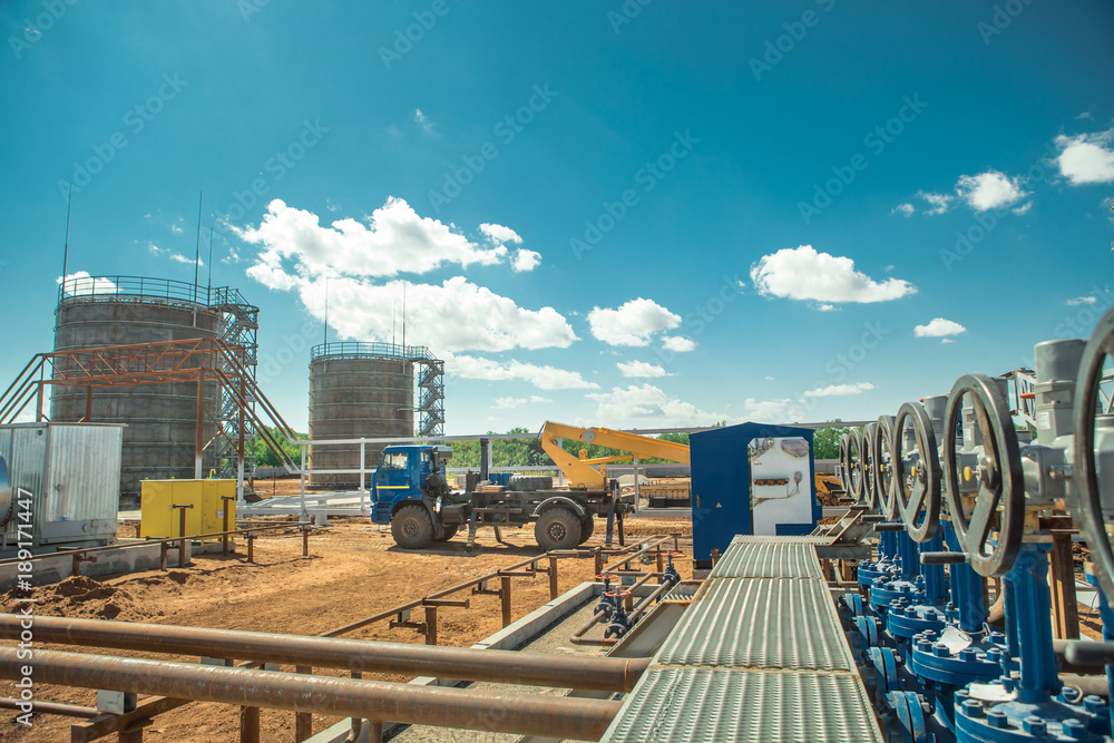 Oilfield development, big oil tanks on the background. Oilfield development, big oil tanks on the background.