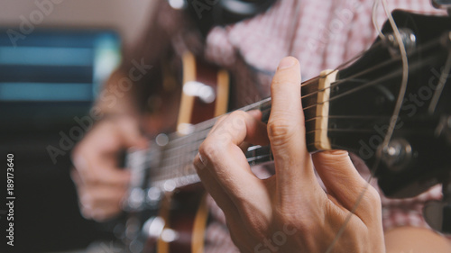 Male musician plays the guitar, hands close up, focus on the guitar fretboard