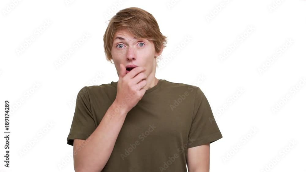 Portrait of man being shocked covering open mouth with hand bulging his eyes over white background closeup in slow motion. Concept of emotions Portrait of man being shocked covering open mouth with hand bulging his eyes over white background closeup in slow motion. Concept of emotions