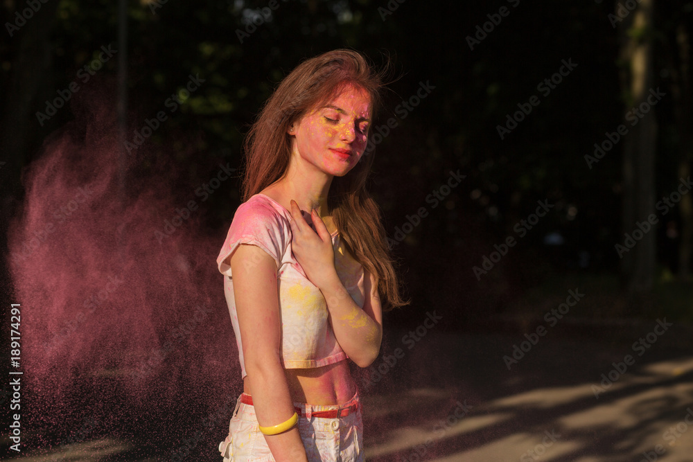 Naklejka premium Charming young woman posing with pink powder Holi exploding around her