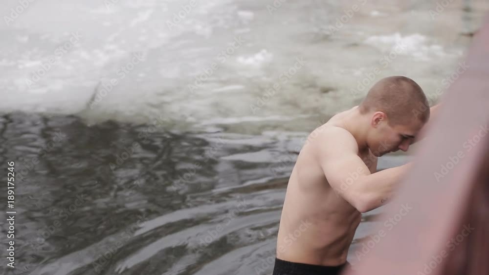 A young guy dives into the icy water of a frozen river. Folk traditions. Healthy lifestyle. Winter hardening with ice water A young guy dives into the icy water of a frozen river. Folk traditions. Healthy lifestyle. Winter hardening with ice water