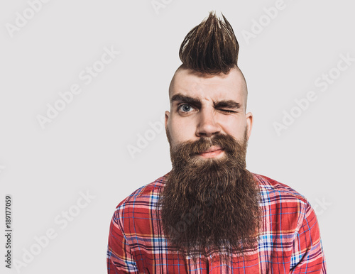 Young trendy man portrait. Excited punk man with Mohawk hairstyle. Isolated on gray background photo
