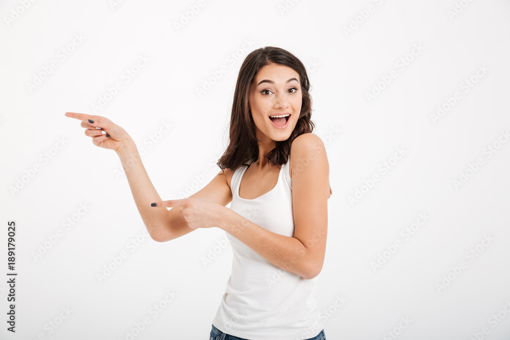 Portrait of a happy girl dressed in tank-top pointing fingers Portrait of a happy girl dressed in tank-top pointing fingers