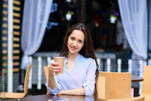 Beautiful woman is drinking coffee in a street cafe.