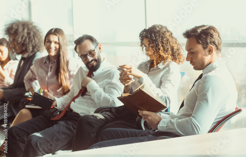 Close up image of business people sitting on office chairs. Everybody loooks busy by planning project.