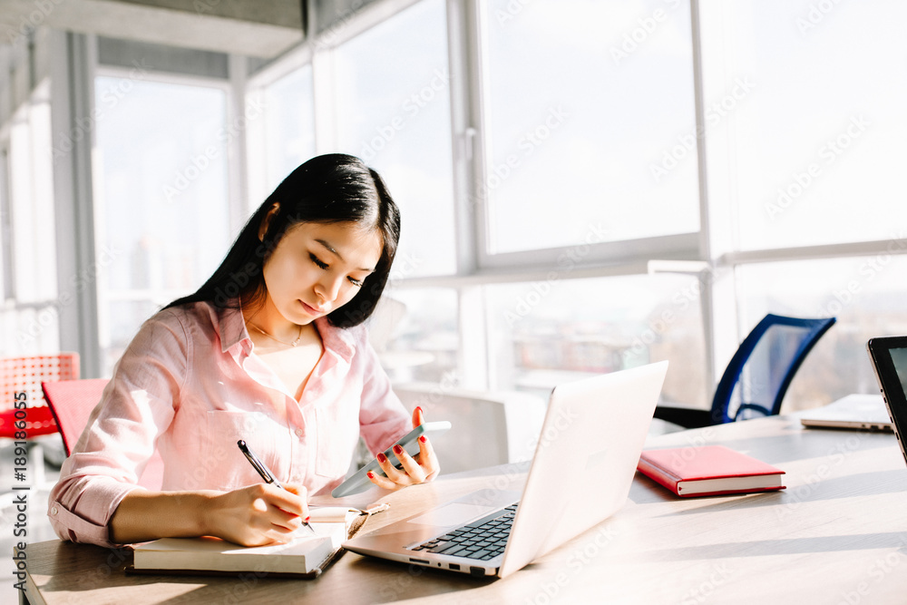 Beautiful female manager sitting at desk and amking notes. Office concept. Beautiful female manager sitting at desk and amking notes. Office concept.