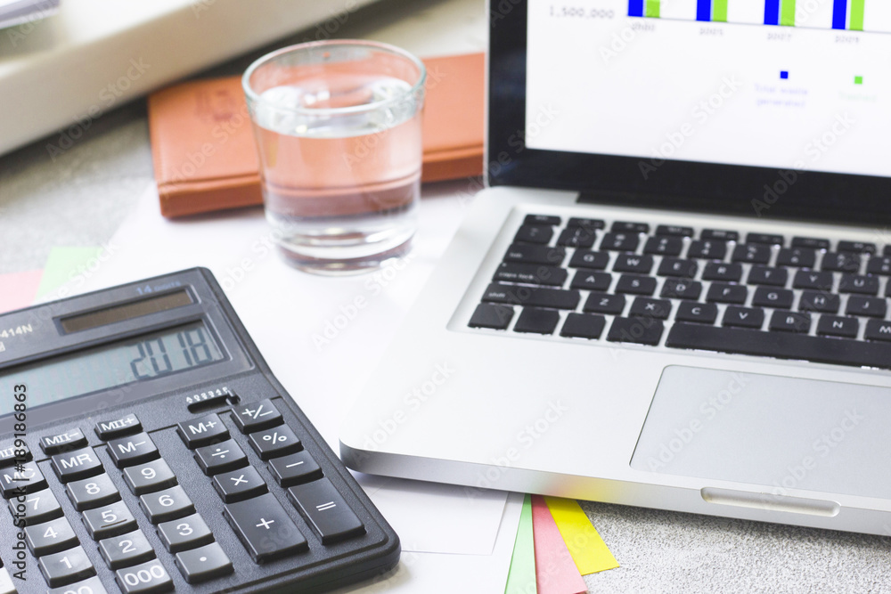 Business Workplace, Analysis, Finance Concept with a laptop, and a calculator, close up, grey concrete background Business Workplace, Analysis, Finance Concept with a laptop, and a calculator, close up, grey concrete background
