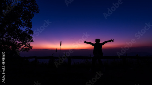 The silhouette of women and men is watching the sunset happily.