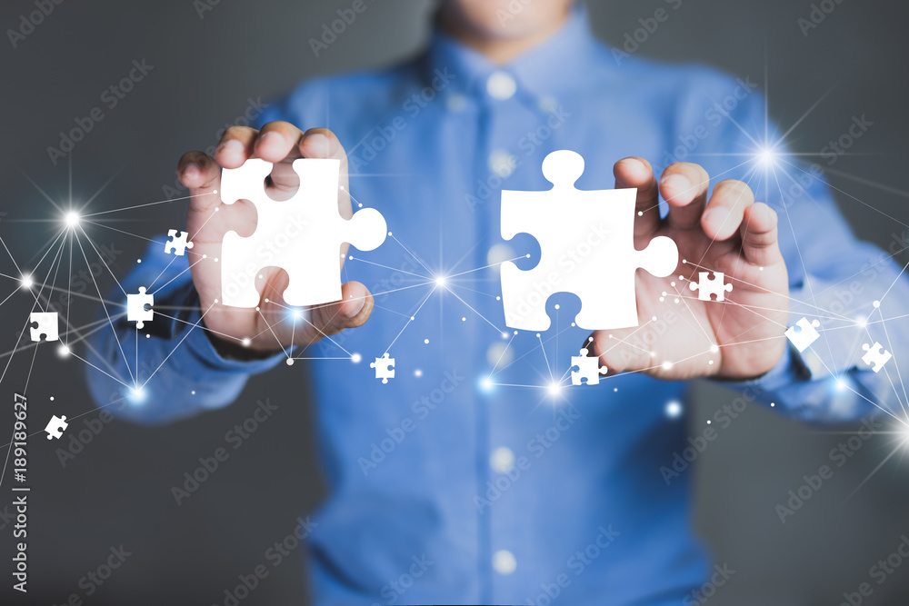 Businessman hands connecting puzzle pieces representing the merging of two companies or joint venture, partnership, Mergers and acquisition concept. - obrazy, fototapety, plakaty 