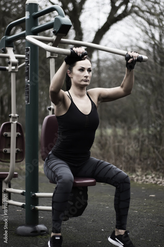 Fitness young woman using outdoor gym equipment in the park