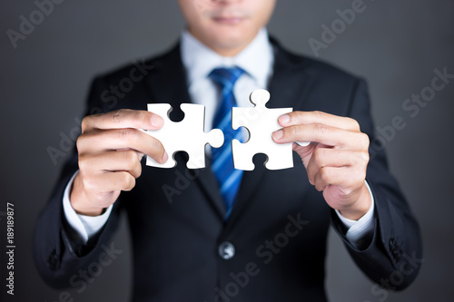 Bilde på lerret Businessman hands connecting puzzle pieces representing the merging of two companies or joint venture, partnership, Mergers and acquisition concept