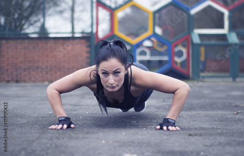Fitness woman doing push-ups during outdoor cross training workout. Beautiful young and fit fitness sport model training outside