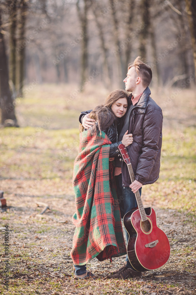 couple walking in a romantic mood with guitar outdoors in a park.