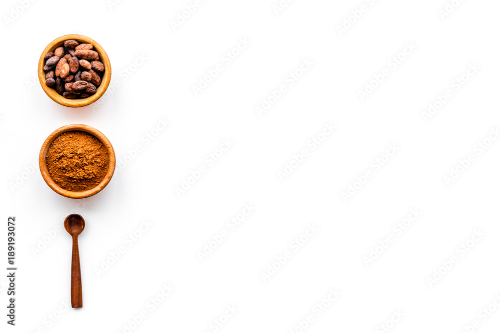 Fototapeta premium Main ingredient for chocolate. Cocoa powder in bowl near cocoa beans on white background top view copy space