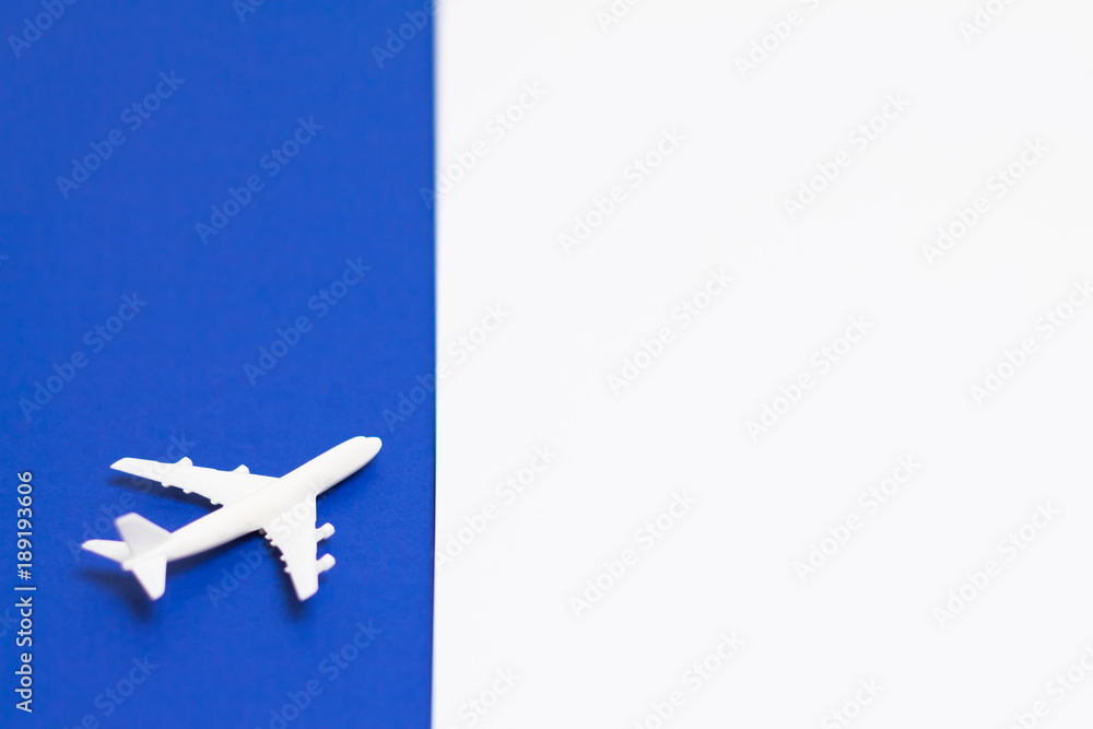 Fototapeta premium Small white plane on top of blue white background