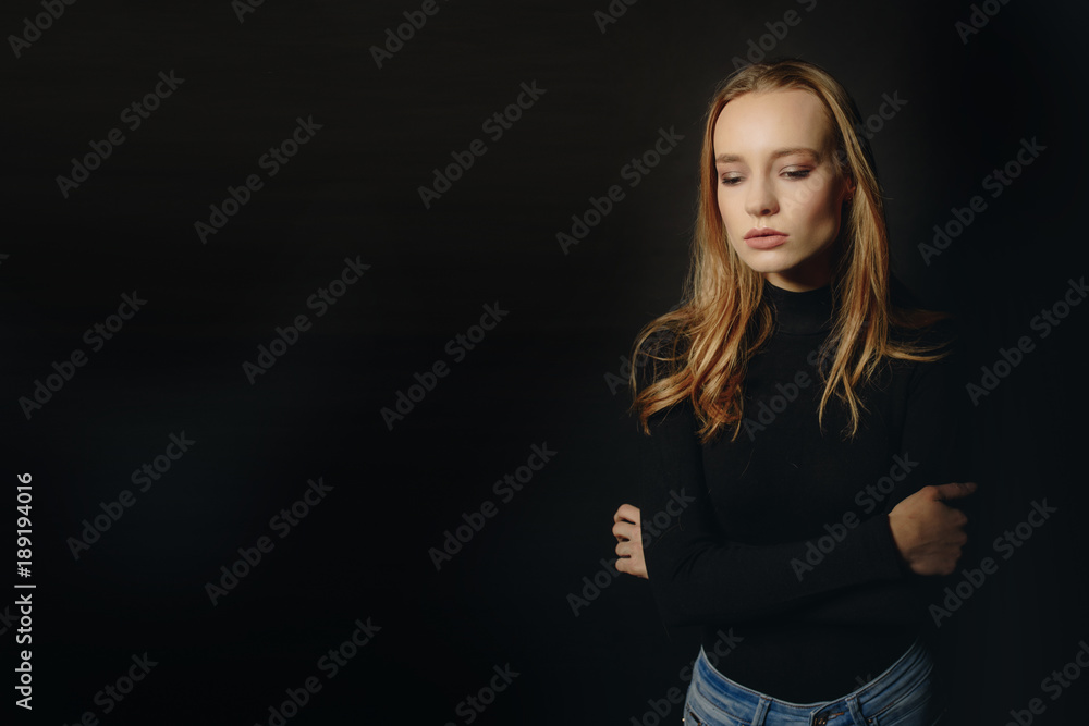 Feeling ready and attraction. Handsome young woman looking at camera. She wears in sweater while standing against black background Feeling ready and attraction. Handsome young woman looking at camera. She wears in sweater while standing against black background