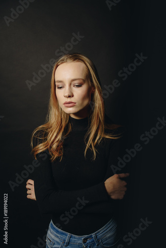 Feeling ready and attraction. Handsome young woman looking at camera. She wears in sweater while standing against black background © vitleo