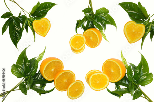 Oranges on a cut one of which in the form of heart with bright green original leaves isolated on a white background