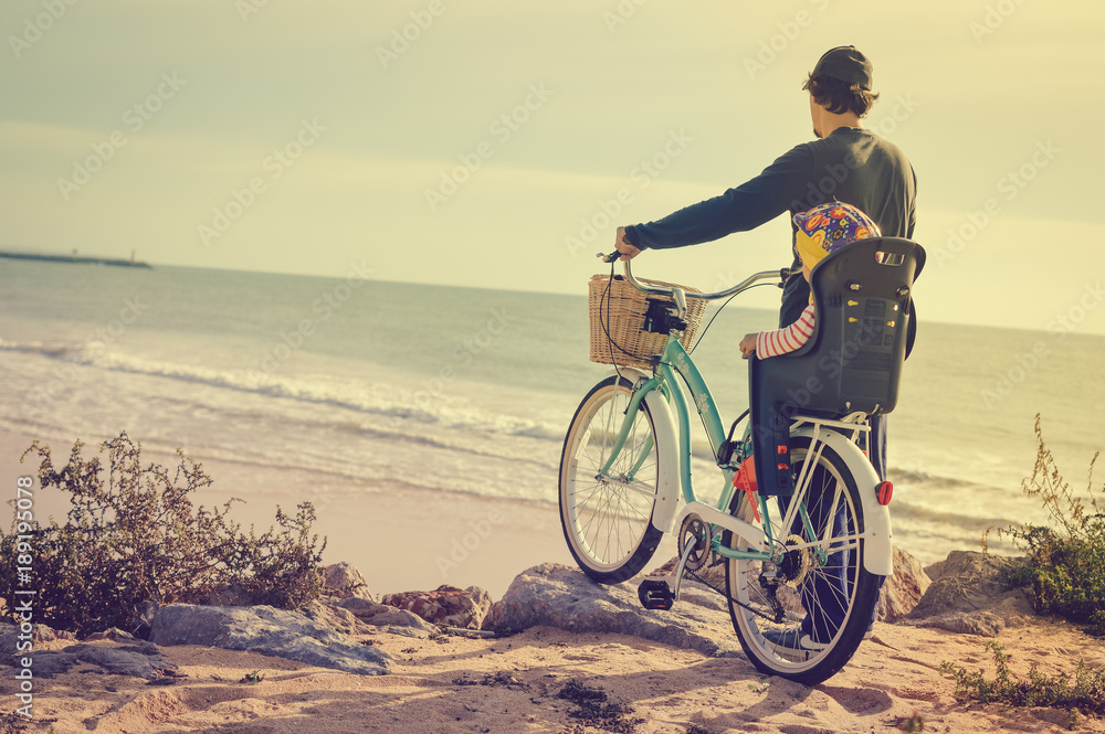 Father and child biking on beach coastline outside nature background. Blurred outdoors image of active family bike ride. Healthy activity lifestyle, having fun travel vacation