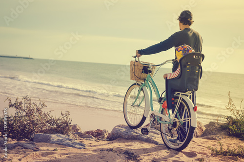 Father and child biking on beach coastline outside nature background. Blurred outdoors image of active family bike ride. Healthy activity lifestyle, having fun travel vacation photo