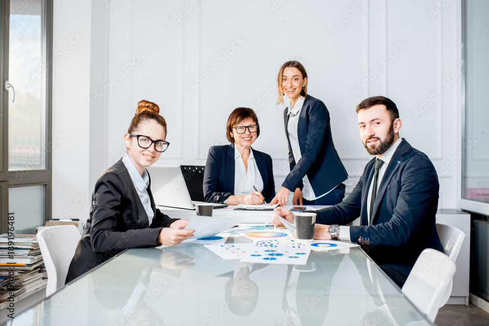 Portrait of a business people working with charts and documents sitting at the table during the conference in the office Portrait of a business people working with charts and documents sitting at the table during the conference in the office