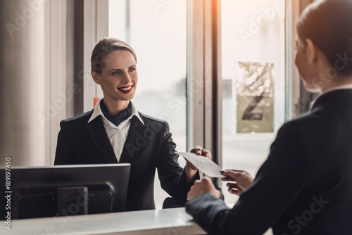 young businesswoman giving ticket to staff at airport check in counter photo