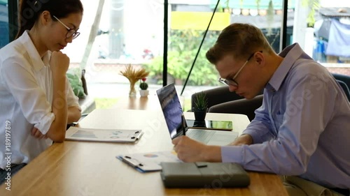 caucasian student using computer for learning leasson online at cafe. startup man & asian woman working at office.  young entrepreneur analyze financial data at workplace. business, education concept photo