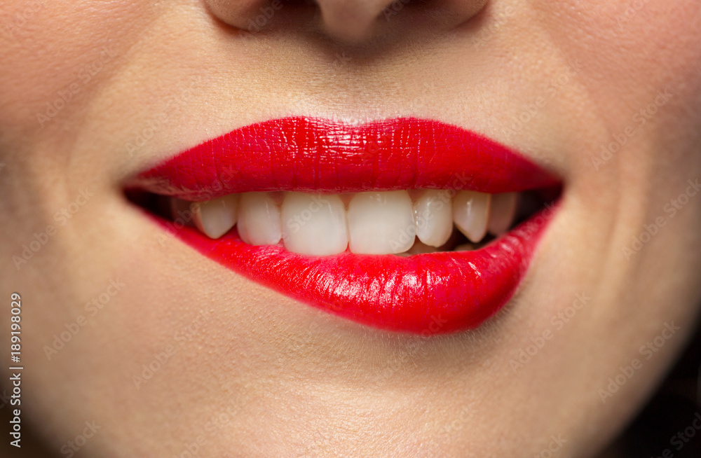 close up of woman with red lipstick biting lip close up of woman with red lipstick biting lip