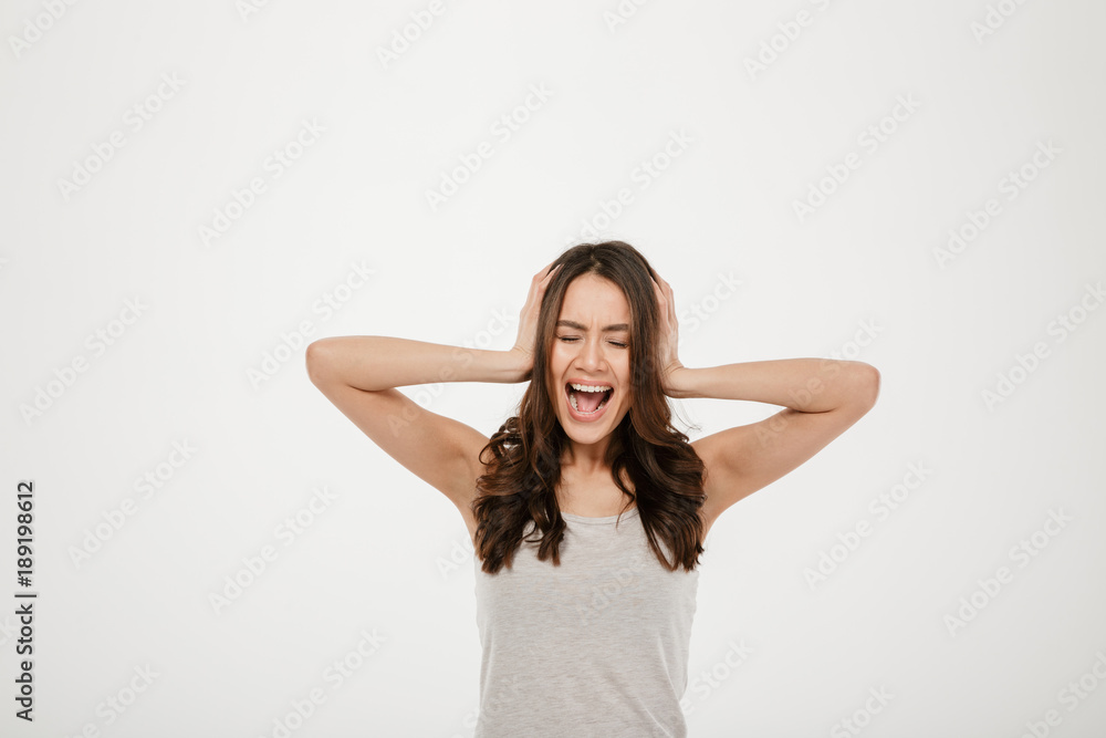 Image of Angry brunette woman screaming and covering her ears Image of Angry brunette woman screaming and covering her ears