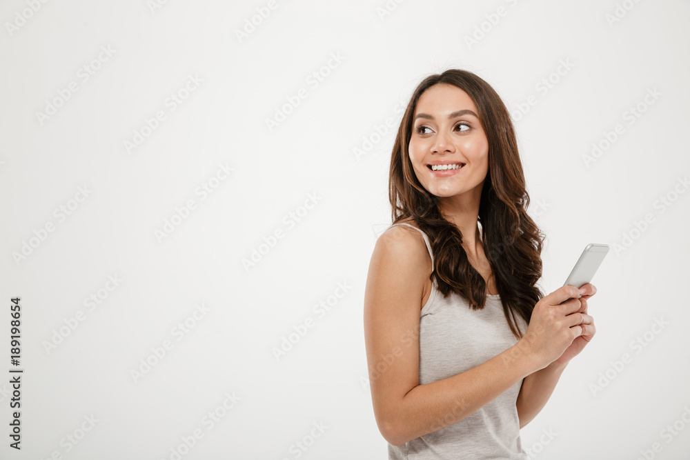 Side view of happy woman holding smartphone and looking back Side view of happy woman holding smartphone and looking back
