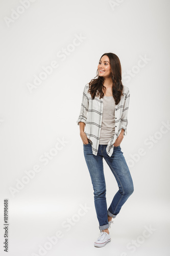 Full length image of Pleased brunette woman in shirt posing