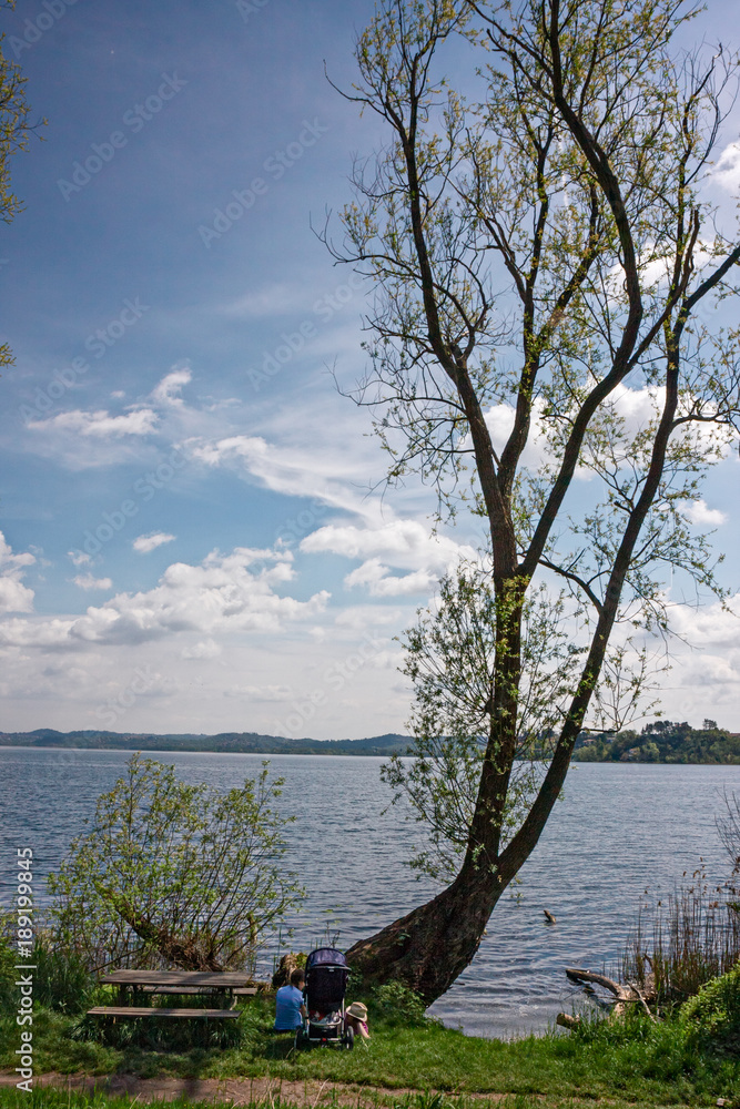 Fototapeta premium A couple of people relax by the lake on a spring afternoon.