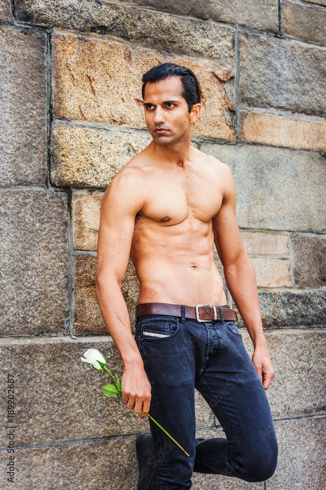 667px x 1000px - Young East Indian American Man, half naked, showing strong body, wearing  black jeans, holding white rose, standing by rock wall in New York, looking  away, waiting for you.. Stock Photo | Adobe
