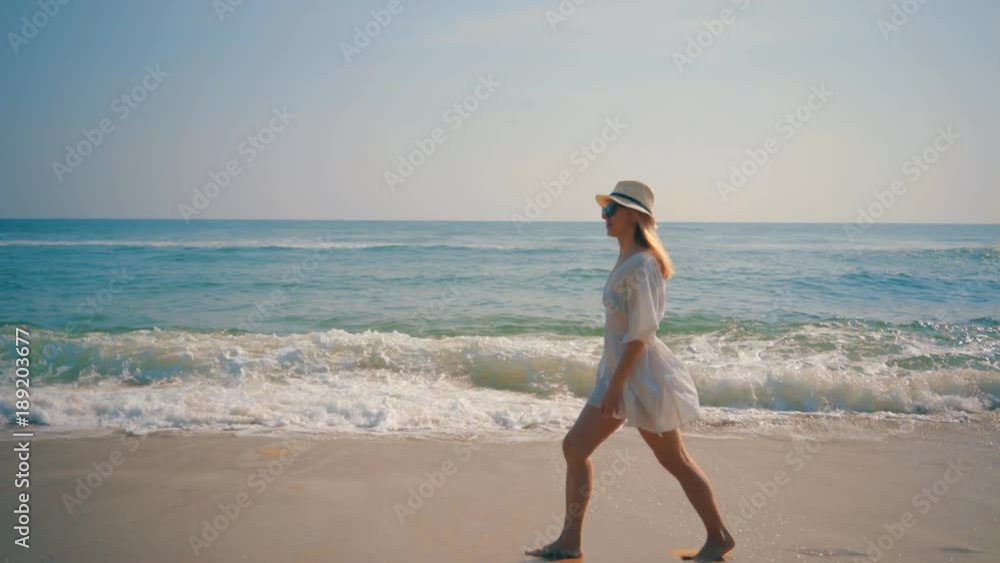 Woman wallking on the ocean beach under blue sky in sunny day. Seascape view with palms. Woman wallking on the ocean beach under blue sky in sunny day. Seascape view with palms.