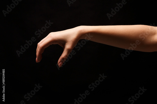 Female hand picking up something, cutout on black