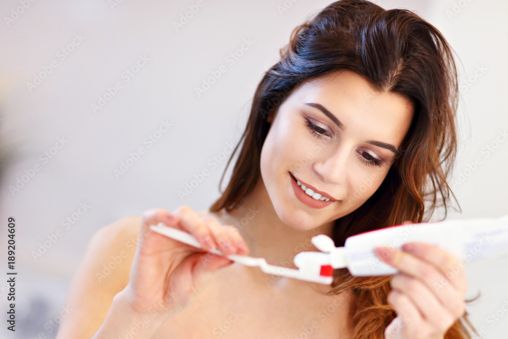 Young woman washing teeth in bathroom in the morning Young woman washing teeth in bathroom in the morning