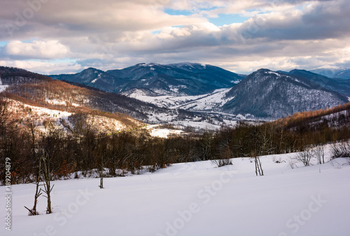 beautiful mountainous countryside in afternoon. gorgeous winter landscape with cloudy sky and snowy slopes