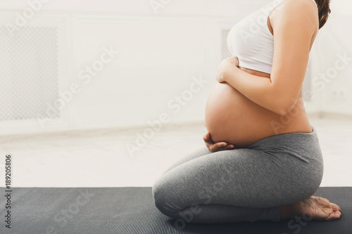 Fototapeta Naklejka Na Ścianę i Meble -  Unrecognizable pregnant woman training yoga in lotus pose
