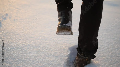 Legs of man walking on snow with footprints on snowy day