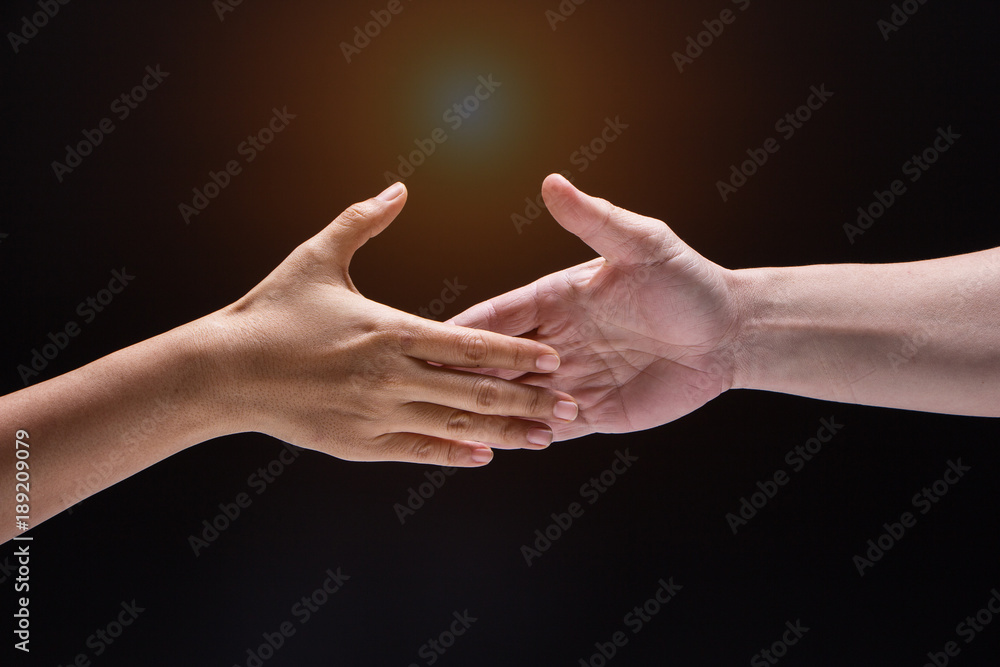 Closeup human hand ,between mand and woman.they are reaching to touch together,the sign and symbol of friendship,collaborate,trust and love,blurry light around.