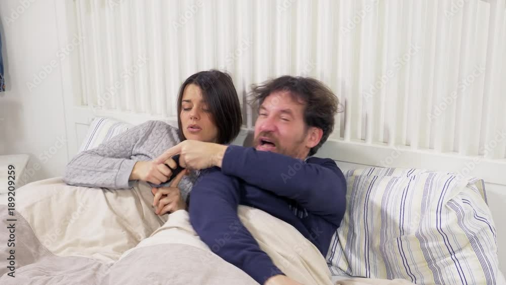 Woman in bed discovering man cheating with lover on phone Woman in bed discovering man cheating with lover on phone