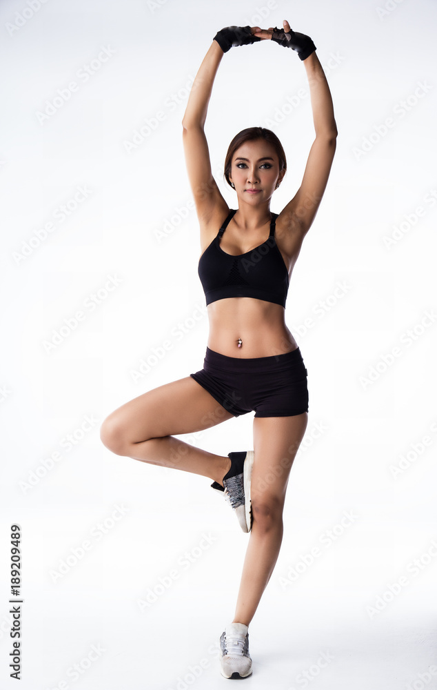 The lady in exercise suit is standing on ground floor with left leg and put right leg up,Hands above the head and breath ,warm up pattern before exercise The lady in exercise suit is standing on ground floor with left leg and put right leg up,Hands above the head and breath ,warm up pattern before exercise