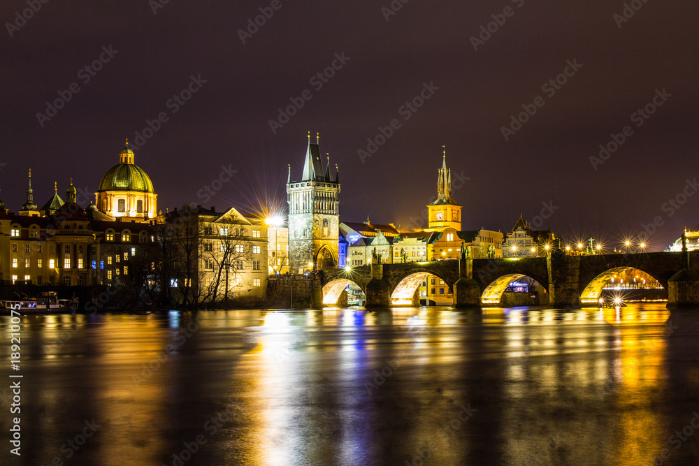 Beautiful night view of the Charles Bridge, the Old Town Bridge Tower, and the Old Water Tower, the Smetana Embankment and the Prague Beer Museum in Czech Republic New Year's Eve