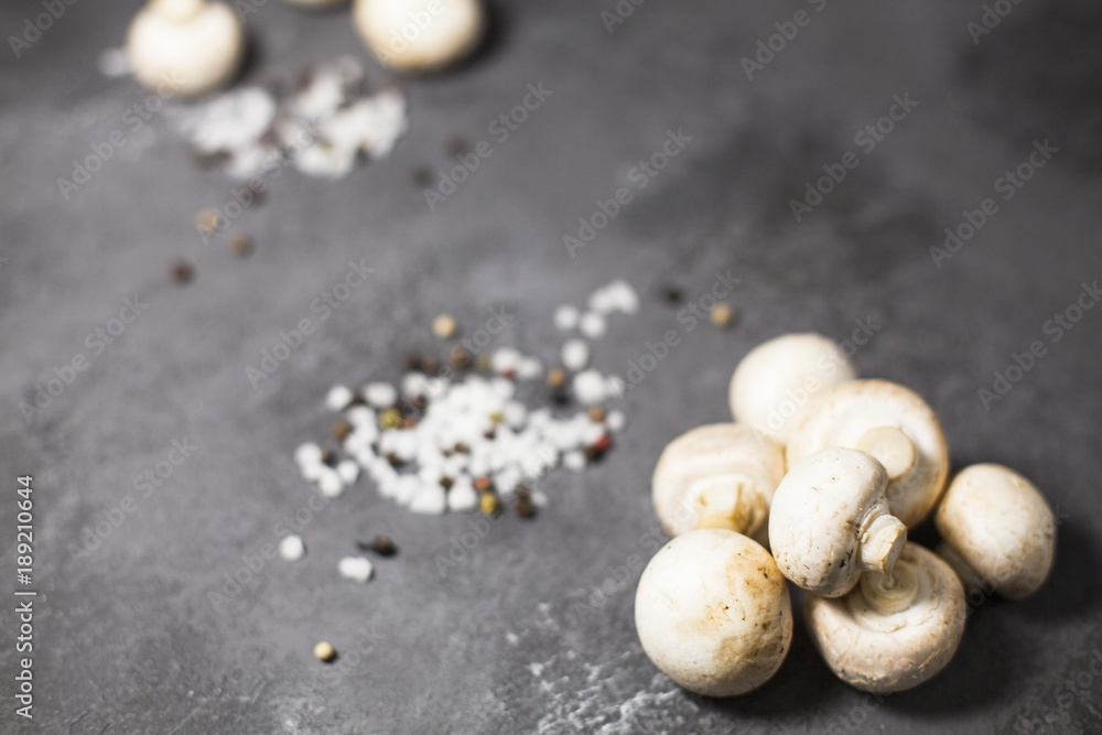 Diet, Italian Food Cooking, Vegetarian Concept. Fresh button mushrooms, sea salt grains and black pepper corns on a dark concrete background, selective focus