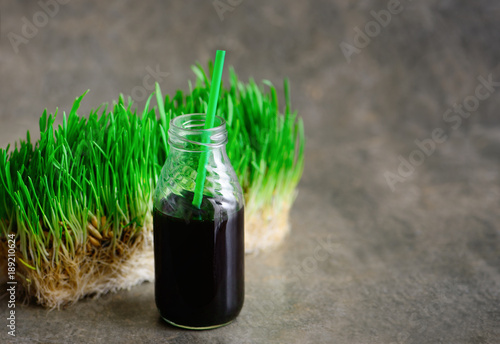 Freshly squized wheatgrass portion in a bottle with a straw photo