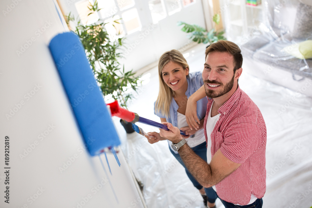 Young happy couple painting walls at new apartment Young happy couple painting walls at new apartment