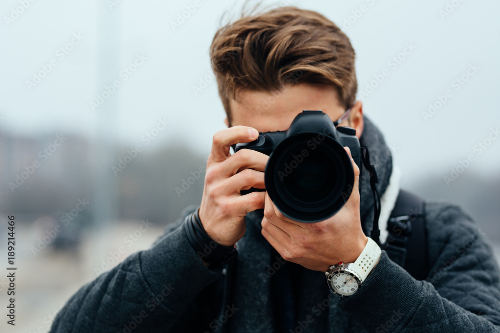 Close up view of professional photographer taking photos outdoors. Dressed in warm jacket. Close up view of professional photographer taking photos outdoors. Dressed in warm jacket.